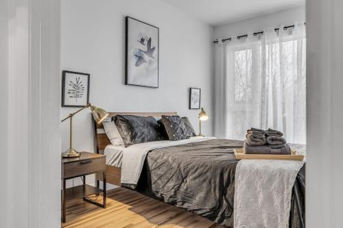a white bedroom with a bed and a window at Initial Artsy Québec in Quebec City