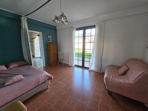 a bedroom with two beds and a couch and a window at Gîte bleu avec piscine chauffée couverte, Bozouls, Aveyron in Bozouls