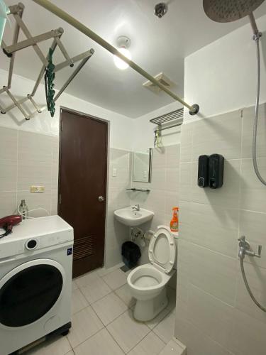 a bathroom with a toilet and a sink and a microwave at Cozy unit in mivesa garden residence in Cebu City