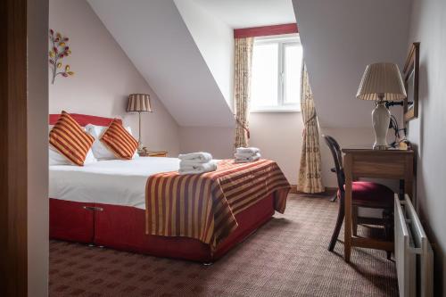 a bedroom with a bed and a desk and a window at Viking House Hotel Donegal in Kincasslagh