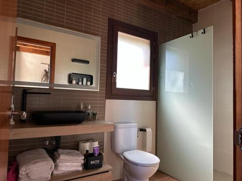 a bathroom with a white toilet and a window at Can Roura in Rocabruna