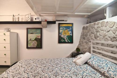 a bedroom with a bed and three paintings on the wall at Casa Vacanza La Giosa in Sperlonga