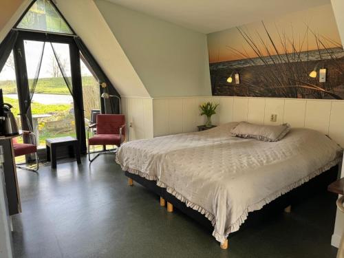 a bedroom with a bed and a large window at Hotelhuisjes Oosterleek in Oosterleek