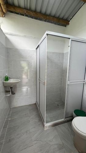 a bathroom with a shower and a toilet and a sink at Cabaña El Tucan in Minca