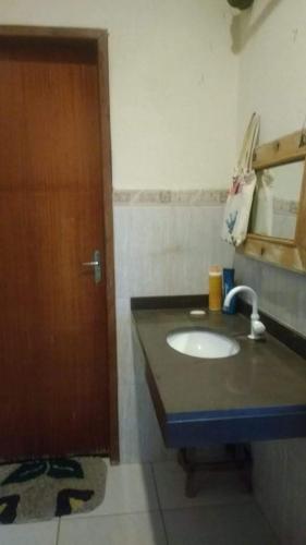 a bathroom with a sink and a wooden door at Sossego e Lazer na Serra do Cipó, piscina e Rio in Jaboticatubas