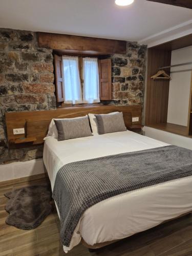 a bedroom with a large bed with a stone wall at Loft Miradas al Sella in Corigos