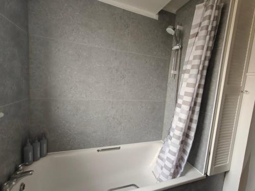 a bath tub with a shower curtain in a bathroom at Spacious Double Room - Shared Bathroom - Zone 2 - Smart Lock Entry - No Check In Hassle in London