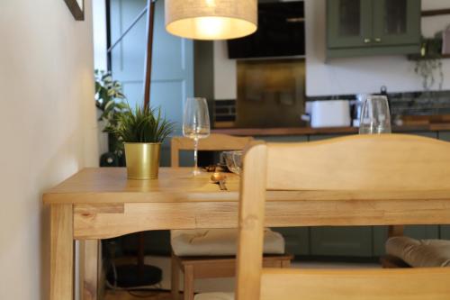 a wooden table with two wine glasses on it at Stone & Sage- City Centre Luxury Courtyard Lofts in Lancaster
