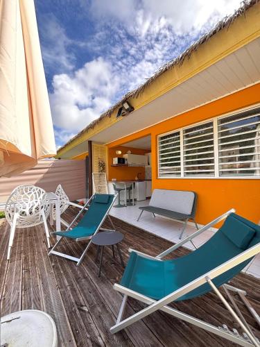 a deck with chairs and a table and a house at Bungalow Agathe - Piscine, Wifi, Farnienté et Plage à 2 minutes in Grand-Bourg