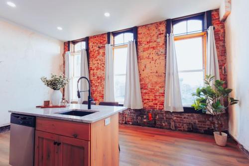 a kitchen with a sink and a brick wall at American Hall - Kaufman Suite in Millersburg