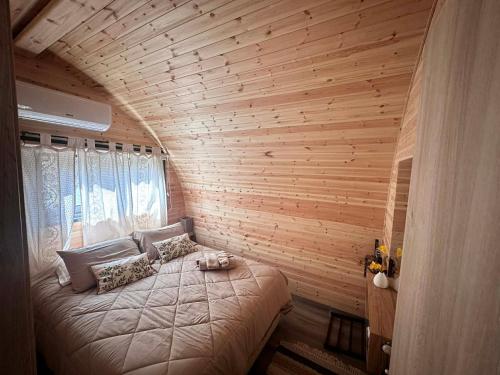 a bedroom with a large bed in a wooden wall at Casa Leandro glamping wooden tiny house in Lachi
