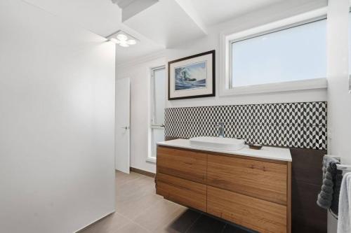 a bathroom with a sink and a window at Beachfront Beauty Bellerive in Bellerive