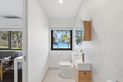 a white bathroom with a sink and a mirror at Modern Beachside Studio in Kingston Beach
