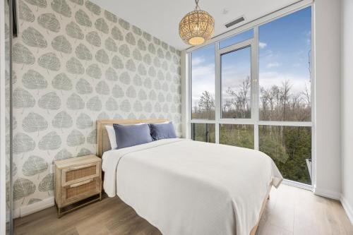 ein Schlafzimmer mit einem Bett und einem großen Fenster in der Unterkunft Lake Simcoe Stays - Friday Harbour's Official Rental Program - Aspen Suite in Innisfil