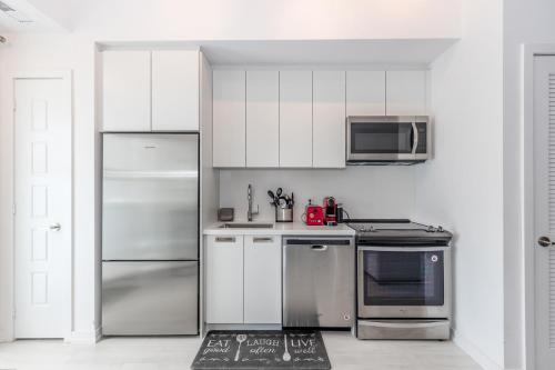eine Küche mit Edelstahlgeräten und weißen Schränken in der Unterkunft Lake Simcoe Stays - Friday Harbour's Official Rental Program - Beech Suite in Innisfil