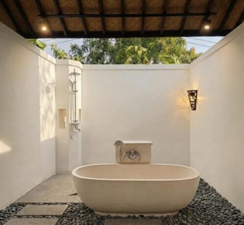 a bath tub in a bathroom with a sink at Sardja Uluwatu in Uluwatu