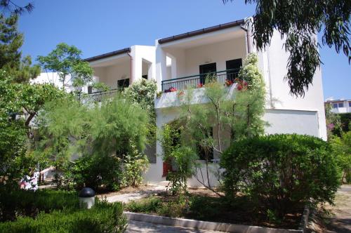 a white house with trees in front of it at Baia Degli Aranci Suite & Apartments in Vieste