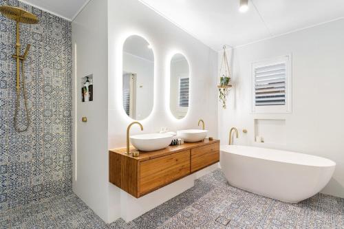 a bathroom with two sinks and two mirrors at Coastal Waterfront Broadbeach Waters in Gold Coast