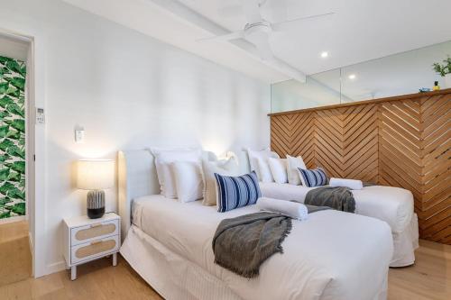 two beds in a white room with a mirror at Coastal Waterfront Broadbeach Waters in Gold Coast