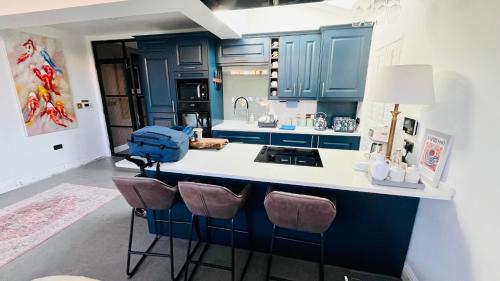 a kitchen with blue cabinets and a sink and stools at Grass Court Terrace - walking distance from Wimbledon Championships in London