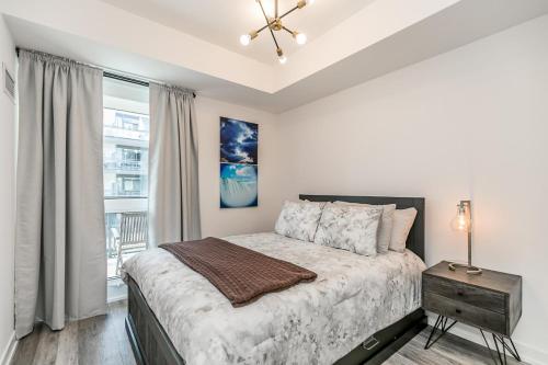 ein weißes Schlafzimmer mit einem Bett und einem Fenster in der Unterkunft Lake Simcoe Stays - Friday Harbour's Official Rental Program - Tamarack Suite in Innisfil