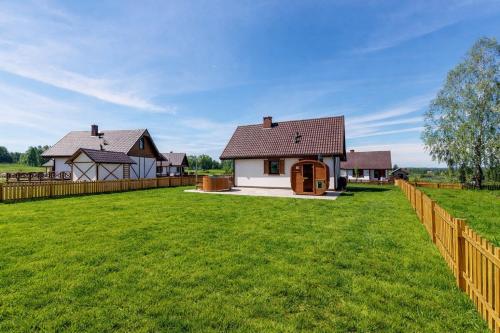 a house with a fence and a green yard at Warmia Prestige in Woryty