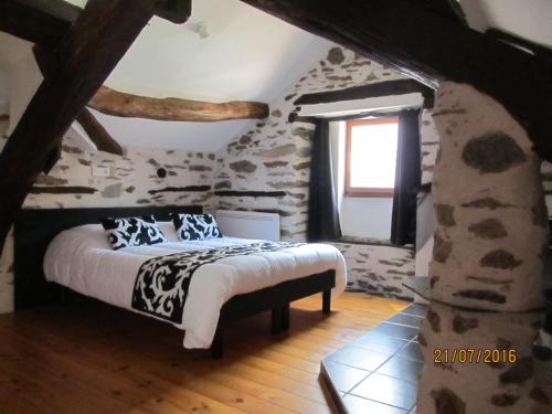 a bedroom with a bed in a stone wall at Chambres d'Hôtes Auberg'inn in Ambialet