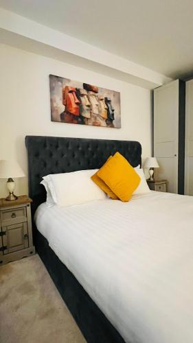 a bed with a yellow pillow on top of it at Grass Court Terrace - walking distance from Wimbledon Championships in London