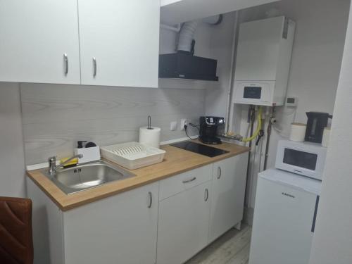 a kitchen with white cabinets and a sink and a microwave at Central Studio in Târgu Secuiesc