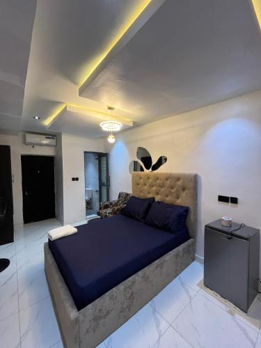 a bedroom with a large bed with a blue blanket at Studio Apartment with Rooftop & Pool Access in Lagos