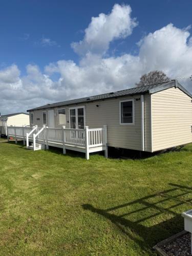 a mobile home with a porch and a yard at Serenity 2 and Serenity 1 Central lounge sleeps 6 3 bedrooms with 2 bathroom in Carlton Colville