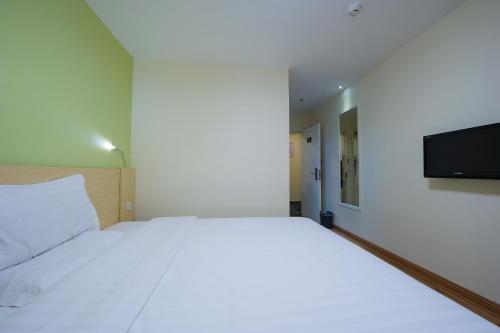 a bedroom with a large white bed and a flat screen tv at 7Days Inn Beijing Jiugong in Daxing
