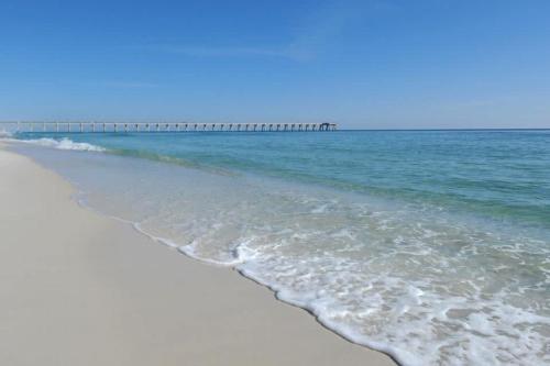 a sandy beach with a pier in the ocean at Sand Dollar E201 in Pensacola Beach