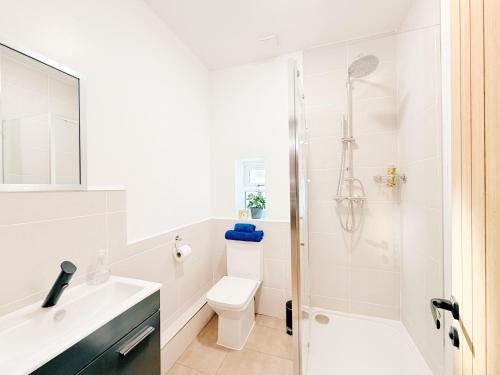 a white bathroom with a toilet and a shower at Spacious Preston Circus Flat - Great for Family, Group, Couples - Close to Station in Brighton & Hove