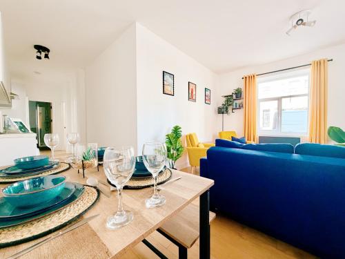 a living room with a blue couch and a table with wine glasses at Spacious Preston Circus Flat - Great for Family, Group, Couples - Close to Station in Brighton & Hove