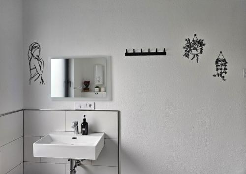 a white bathroom with a sink and a mirror at Luxus-Penthouse mit Panorama-View in Netphen