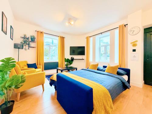 a bedroom with a blue bed and two yellow chairs at Spacious Preston Circus Flat - Great for Family, Group, Couples - Close to Station in Brighton & Hove