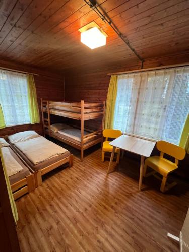 a room with two bunk beds and a table and chairs at Chata Pod Bílým kamenem in Doksy
