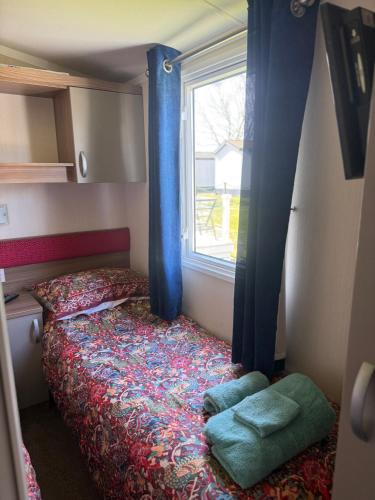 a bedroom with a bed with blue curtains and a window at Serenity 2 and Serenity 1 Central lounge sleeps 6 3 bedrooms with 2 bathroom in Carlton Colville