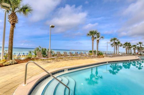 a swimming pool with palm trees and the ocean at Calypso 906W in Panama City Beach
