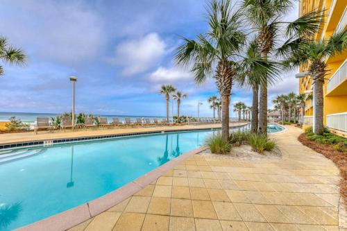 a swimming pool with palm trees next to a building at Calypso 906W in Panama City Beach