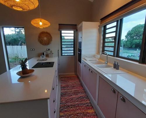a large kitchen with white counters and windows at Chamallow Nature Lodge in Grande Case Noyale