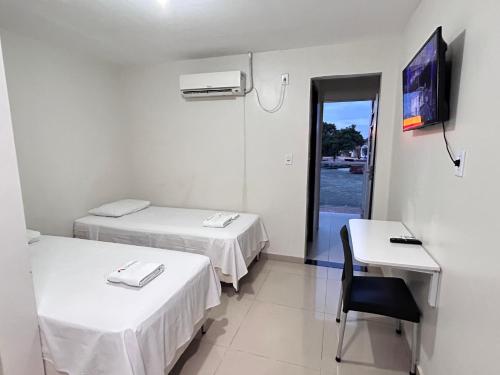 a room with two beds and a table and a television at Rio Hotel in Petrolândia