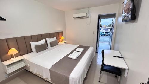 a bedroom with a large bed and a table and chair at Rio Hotel in Petrolândia