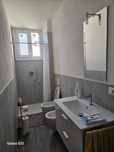 a bathroom with a sink and a toilet and a mirror at Appartamento Torri del Benaco in Torri del Benaco