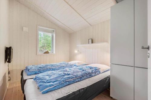 a bedroom with a bed with blue sheets and a refrigerator at VE303-Oksbol-Kaervej-2 in Oksbøl