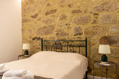 a bedroom with a stone wall with a bed and two lamps at Casa de Algeriz in Algeriz