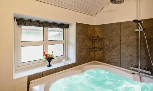a bath tub with a vase of flowers in a bathroom at VE264-Vejers-Strand-Jafdalvej-95 in Vejers Strand