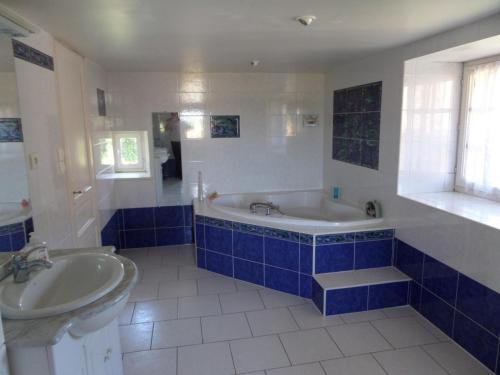 a blue and white bathroom with a tub and a sink at La Roseraie in Romagne