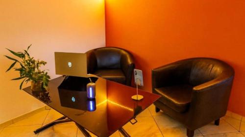 two leather chairs sitting next to a desk with a computer at Hostel des 3 sources in Sainte-Marie